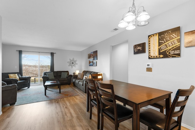 dining space with a notable chandelier and light hardwood / wood-style flooring