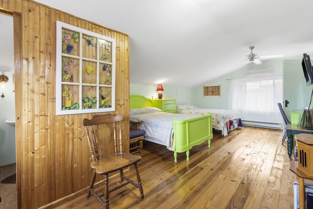 bedroom with a baseboard heating unit, hardwood / wood-style floors, wooden walls, a wall mounted AC, and vaulted ceiling