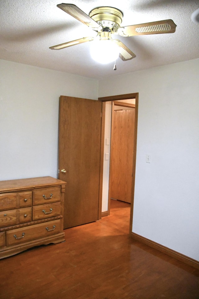 unfurnished bedroom featuring ceiling fan, wood-type flooring, and a textured ceiling