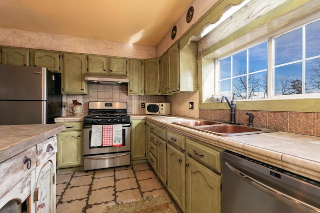 kitchen featuring appliances with stainless steel finishes, tile counters, sink, and decorative backsplash