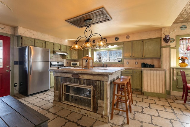 kitchen featuring a kitchen island, decorative light fixtures, a breakfast bar area, green cabinetry, and stainless steel appliances