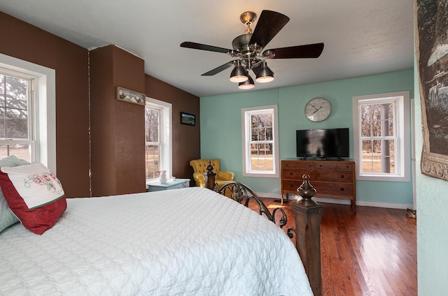 bedroom featuring hardwood / wood-style flooring, ceiling fan, and multiple windows