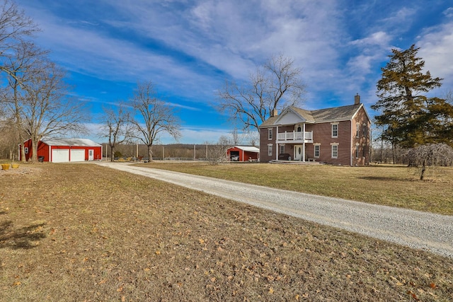 view of yard with a garage, a balcony, and an outbuilding