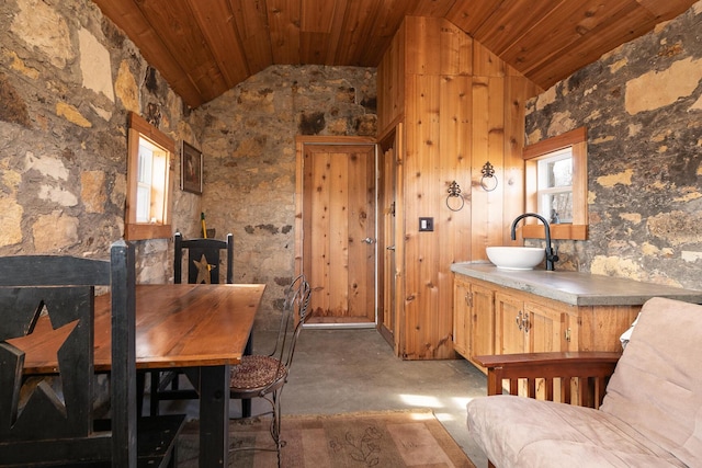 dining space featuring concrete flooring, vaulted ceiling, sink, and wood ceiling