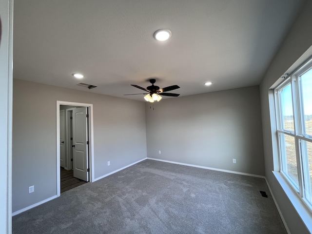 spare room featuring ceiling fan and dark carpet