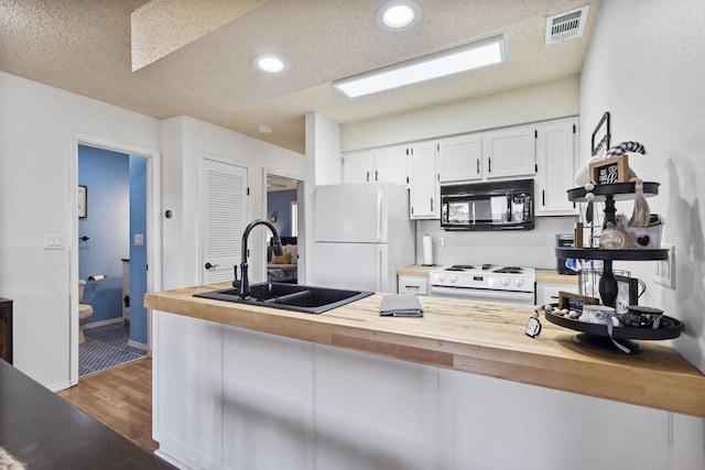 kitchen featuring sink, wooden counters, kitchen peninsula, white appliances, and white cabinets