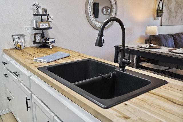 kitchen with wood counters, sink, and white cabinets