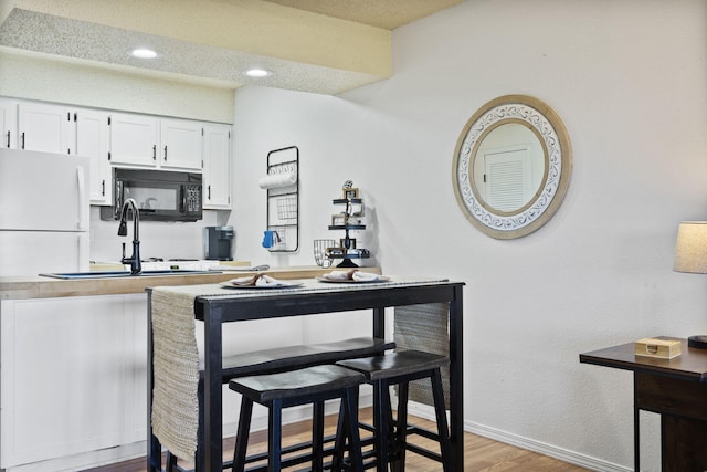 kitchen with white cabinetry, sink, and light hardwood / wood-style floors