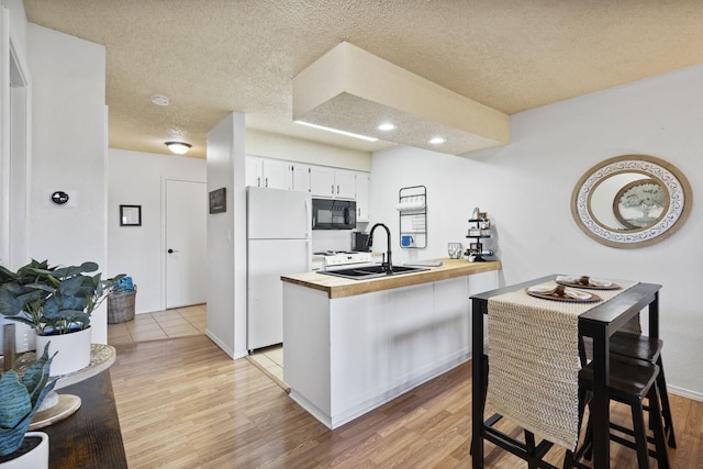 kitchen with butcher block countertops, sink, white cabinets, white refrigerator, and light hardwood / wood-style floors