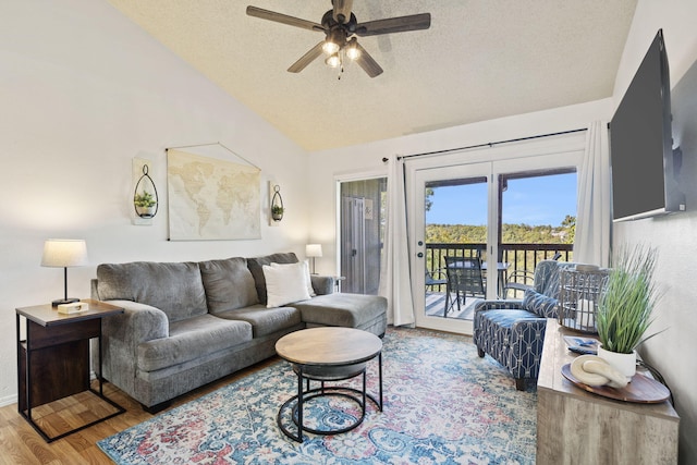 living room featuring ceiling fan, lofted ceiling, hardwood / wood-style floors, and a textured ceiling