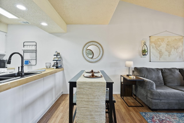 dining room with sink, a textured ceiling, and light hardwood / wood-style flooring