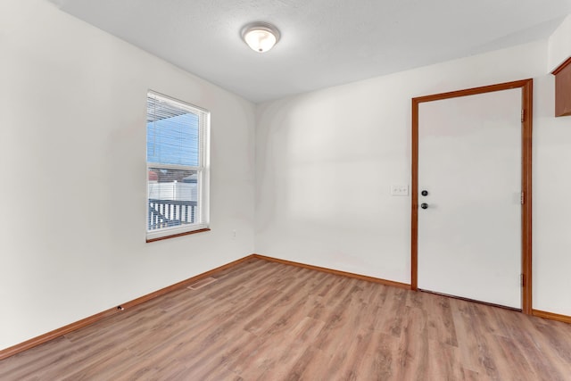 spare room with light hardwood / wood-style flooring and a textured ceiling