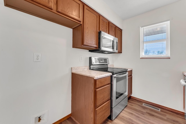 kitchen with appliances with stainless steel finishes and light hardwood / wood-style flooring