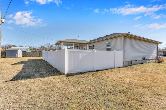 back of house featuring a storage shed and a lawn