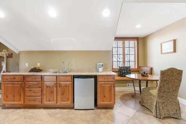 kitchen with stainless steel dishwasher, light countertops, baseboards, and a sink