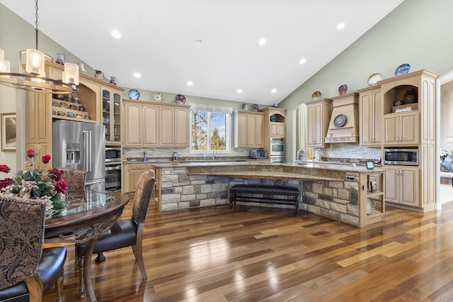 kitchen with a breakfast bar, custom range hood, open shelves, tasteful backsplash, and stainless steel appliances