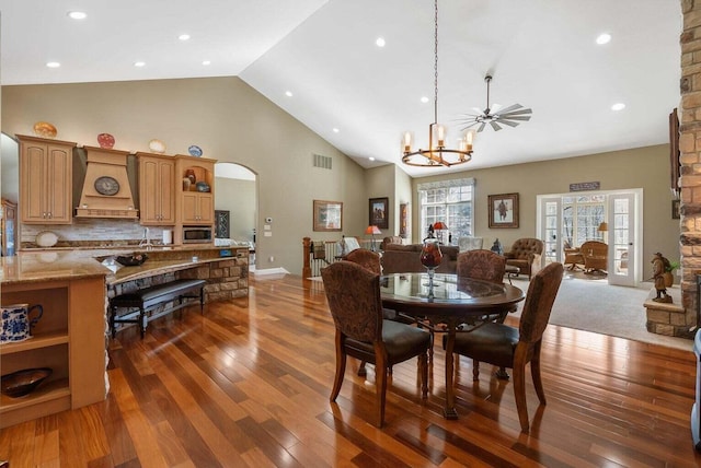 dining room featuring visible vents, high vaulted ceiling, arched walkways, hardwood / wood-style flooring, and a notable chandelier