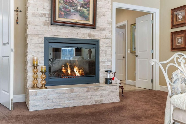 details with baseboards, carpet, and a stone fireplace