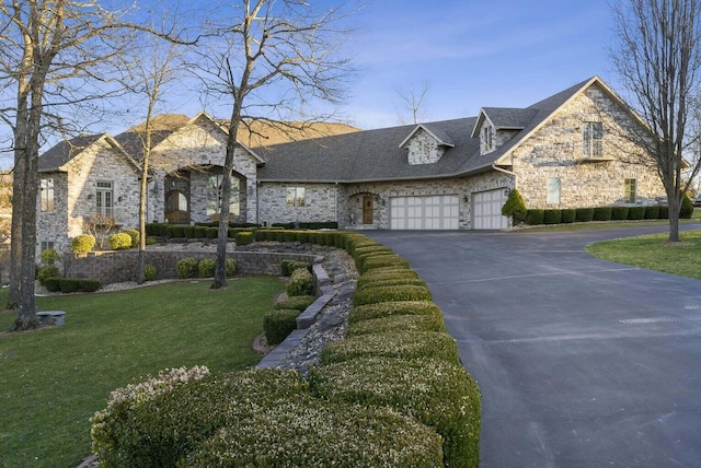 french provincial home featuring aphalt driveway, stone siding, a front yard, and a garage