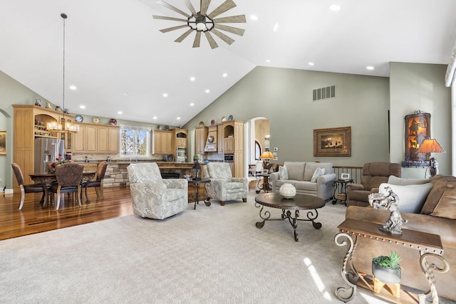 living room featuring an inviting chandelier, high vaulted ceiling, and light hardwood / wood-style flooring