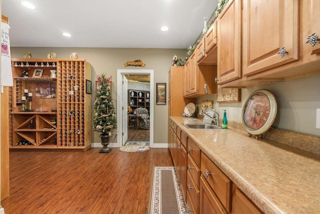 kitchen featuring a sink, dark wood finished floors, recessed lighting, light countertops, and baseboards