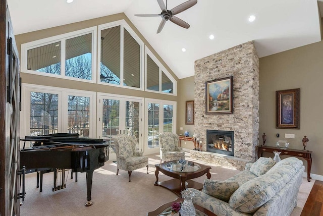 living room featuring ceiling fan, a stone fireplace, and high vaulted ceiling