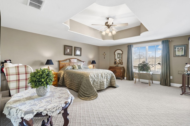 bedroom featuring visible vents, ceiling fan, baseboards, a tray ceiling, and carpet floors