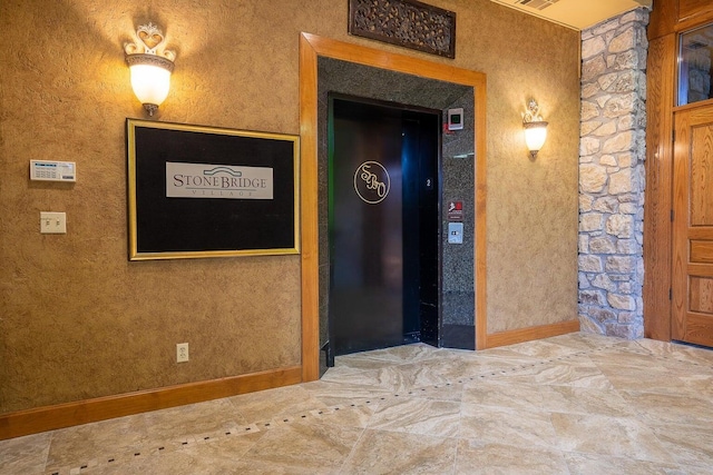 hall featuring baseboards, elevator, and visible vents