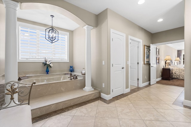 bathroom with a tub, tile patterned floors, and ornate columns