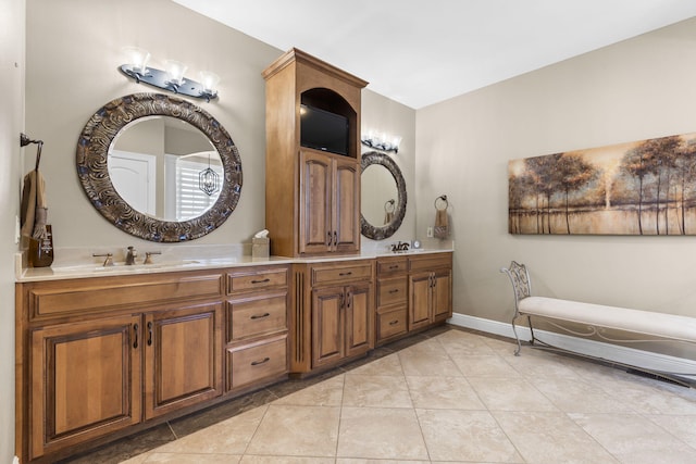 bathroom featuring a sink, baseboards, double vanity, and tile patterned floors