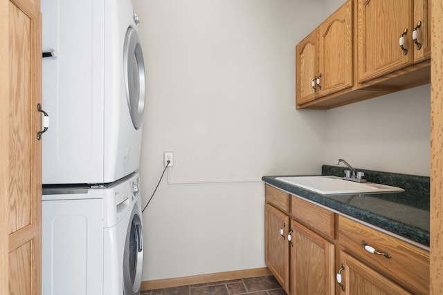 laundry area featuring cabinets, stacked washer / dryer, and sink