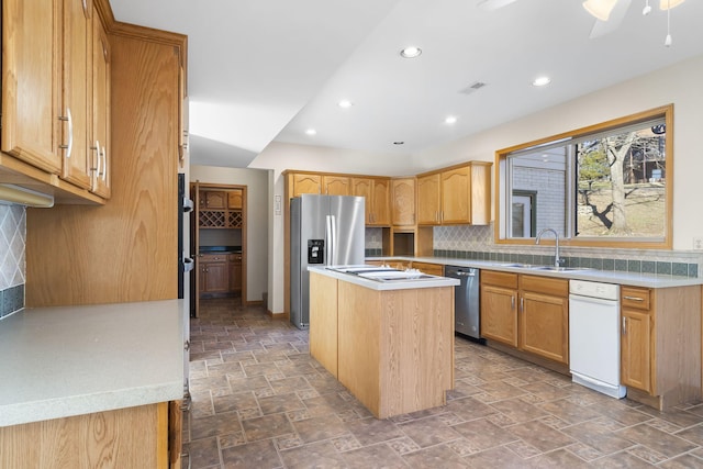 kitchen featuring sink, ceiling fan, appliances with stainless steel finishes, backsplash, and a center island