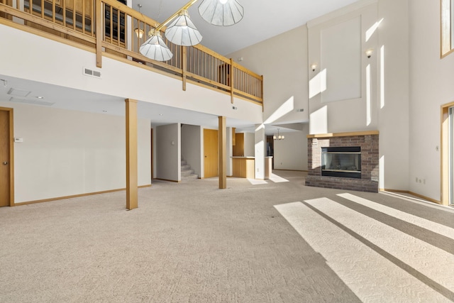 unfurnished living room featuring a brick fireplace, a high ceiling, and carpet