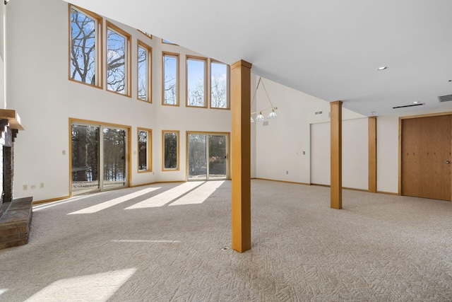 unfurnished living room featuring light colored carpet, a high ceiling, and a wealth of natural light