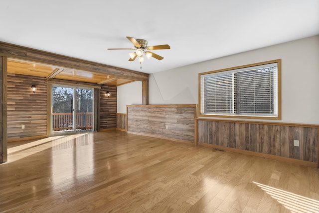 unfurnished room featuring ceiling fan, light hardwood / wood-style flooring, and wood walls