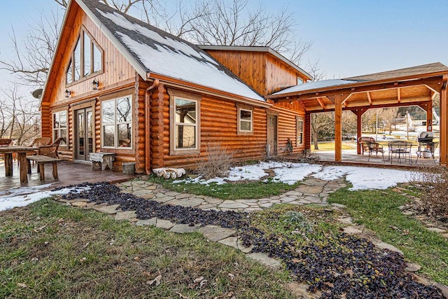 snow covered rear of property with a patio area