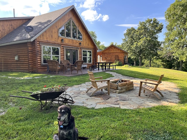 rear view of property with french doors, an outdoor fire pit, a yard, and a patio