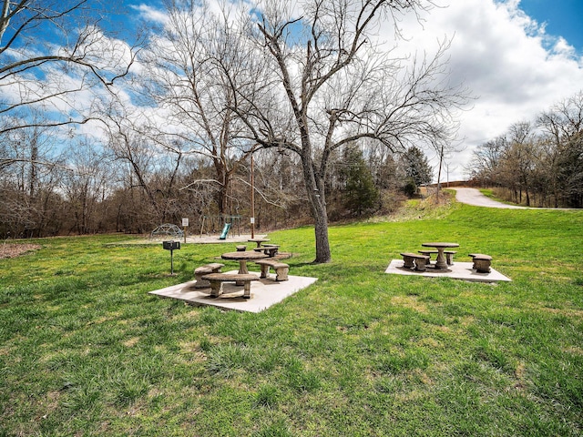 view of property's community featuring a playground, a patio area, and a lawn