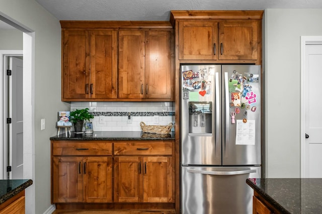 kitchen with tasteful backsplash, dark stone counters, and stainless steel fridge with ice dispenser