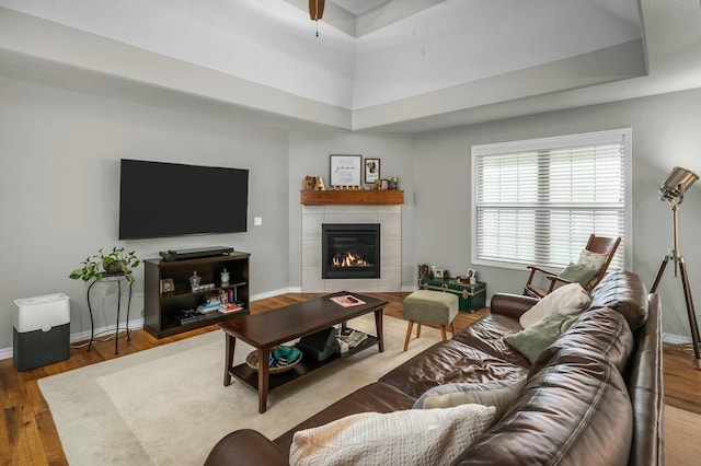 living room with a tiled fireplace and wood-type flooring