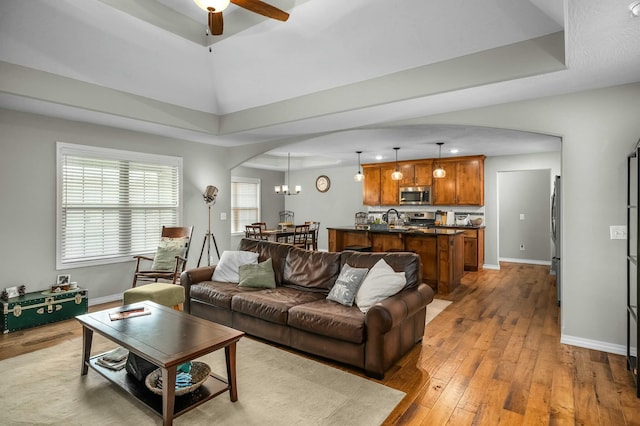 living room featuring ceiling fan, sink, a raised ceiling, and light hardwood / wood-style floors