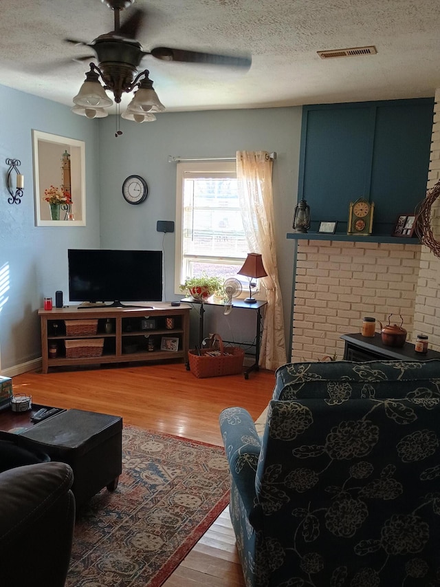 living room with hardwood / wood-style floors, a textured ceiling, and ceiling fan