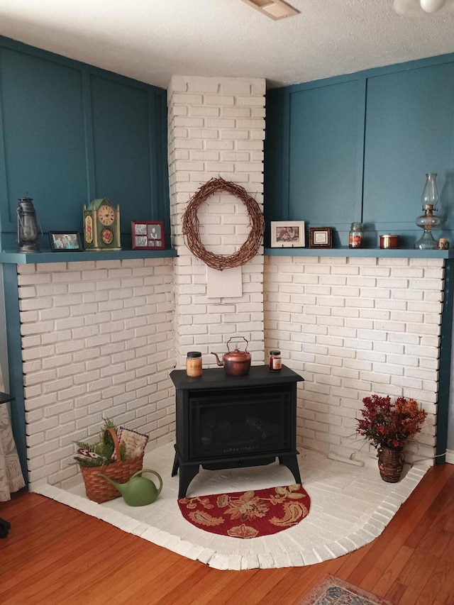 interior details featuring wood-type flooring, a textured ceiling, and a wood stove