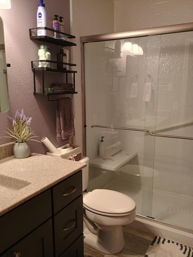 bathroom with a shower with door, vanity, hardwood / wood-style flooring, and toilet