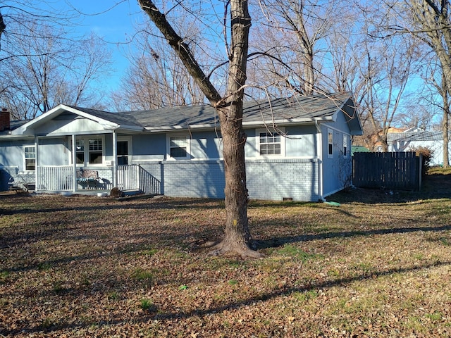 view of front of home featuring a front yard, fence, brick siding, crawl space, and a porch