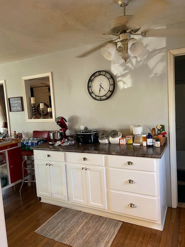 bar with ceiling fan, a textured ceiling, dark hardwood / wood-style floors, and white cabinets