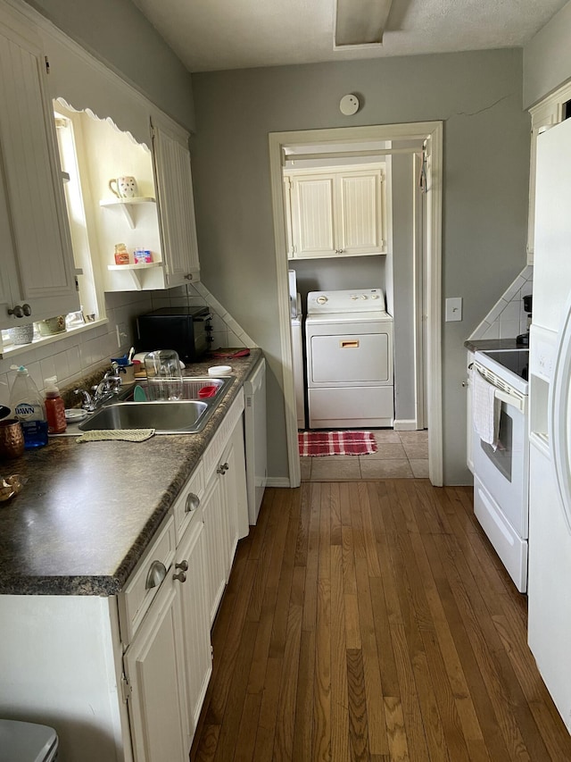 kitchen featuring dark wood-style flooring, electric range, backsplash, a sink, and washer / dryer