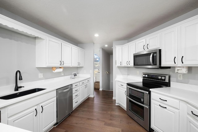 kitchen with appliances with stainless steel finishes, sink, white cabinets, and dark hardwood / wood-style floors