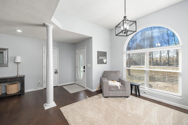 entrance foyer with dark hardwood / wood-style floors, a textured ceiling, and ornate columns