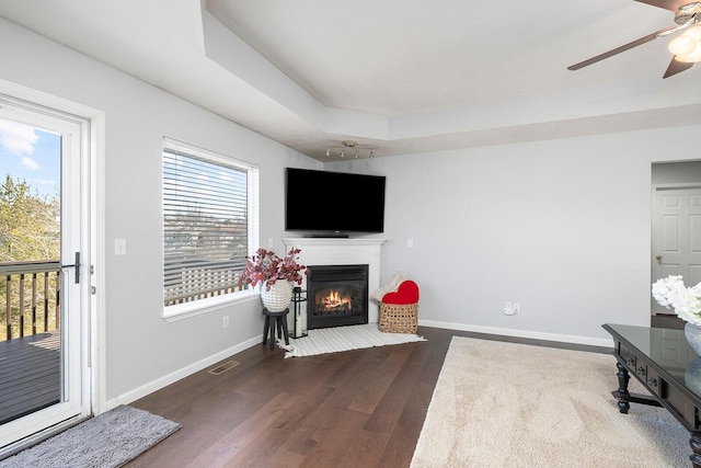 living room featuring hardwood / wood-style flooring, ceiling fan, and a raised ceiling